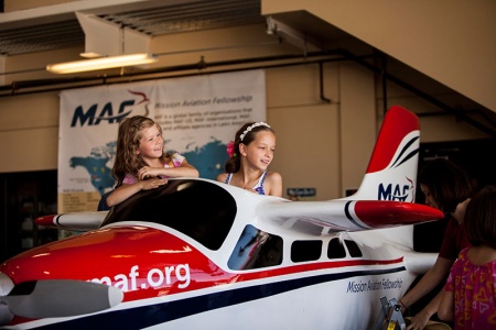 Grace and Faith Olenik of Nampa enjoy a ride on Petey the Plane during MAF’s 70th anniversary celebration. Some 600 people attended the event Saturday at the Nampa airport. Photo by Paul O’Brien.
