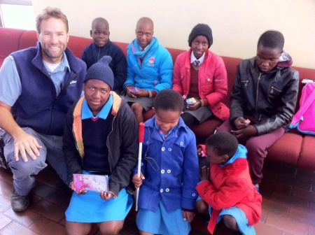 Pilot Bryan Eygabroad with Neheng (back row, light blue jacket), next to Sebongile (in red), and other children being flown to a special school session.